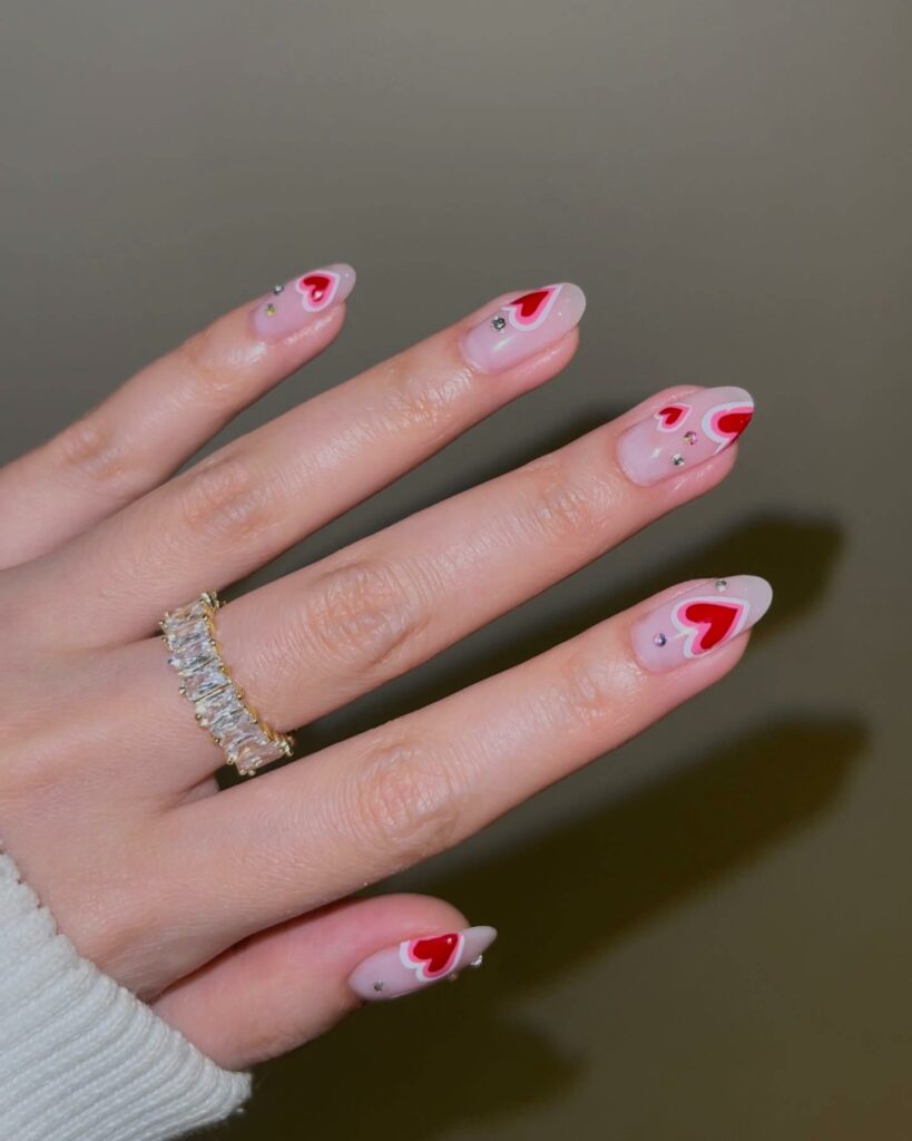 30 Latest Heart Nails Ideas To Try In 2024! 35 Red Hearts On Nude Almond Nails With Rhinestones