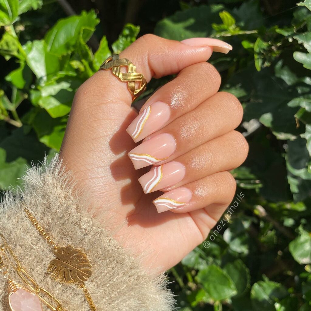 28 Latest Nude And White Nail Designs To Try in 2024! 18 Nude And White Swirl Nails With Gold Glitters