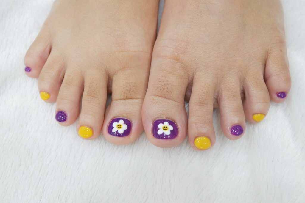 25 Latest Purple Pedicure Designs to Try In 2024! 22 Yellow and Purple Pedicure with Smiley Daisies
