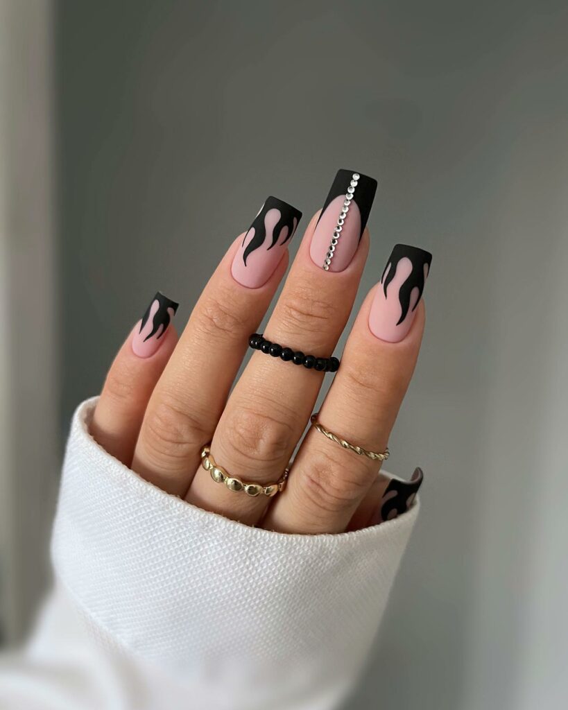 25 Latest Accent Nail Designs To Try In 2024! 29 Matte Black Accent Nails With Flame And Rhinestones Design