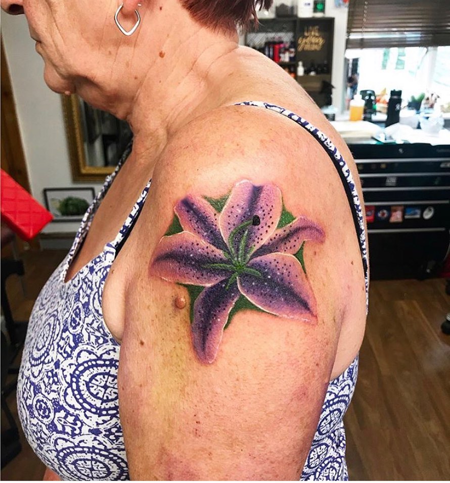 AMAZING LILY TATTOO DESIGNS + A DEEP DIVE INTO THEIR MEANINGS IN 2024 16 Purple Lily Tattoo